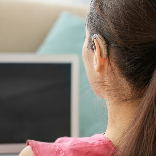 Young woman with hearing aid using laptop indoors
